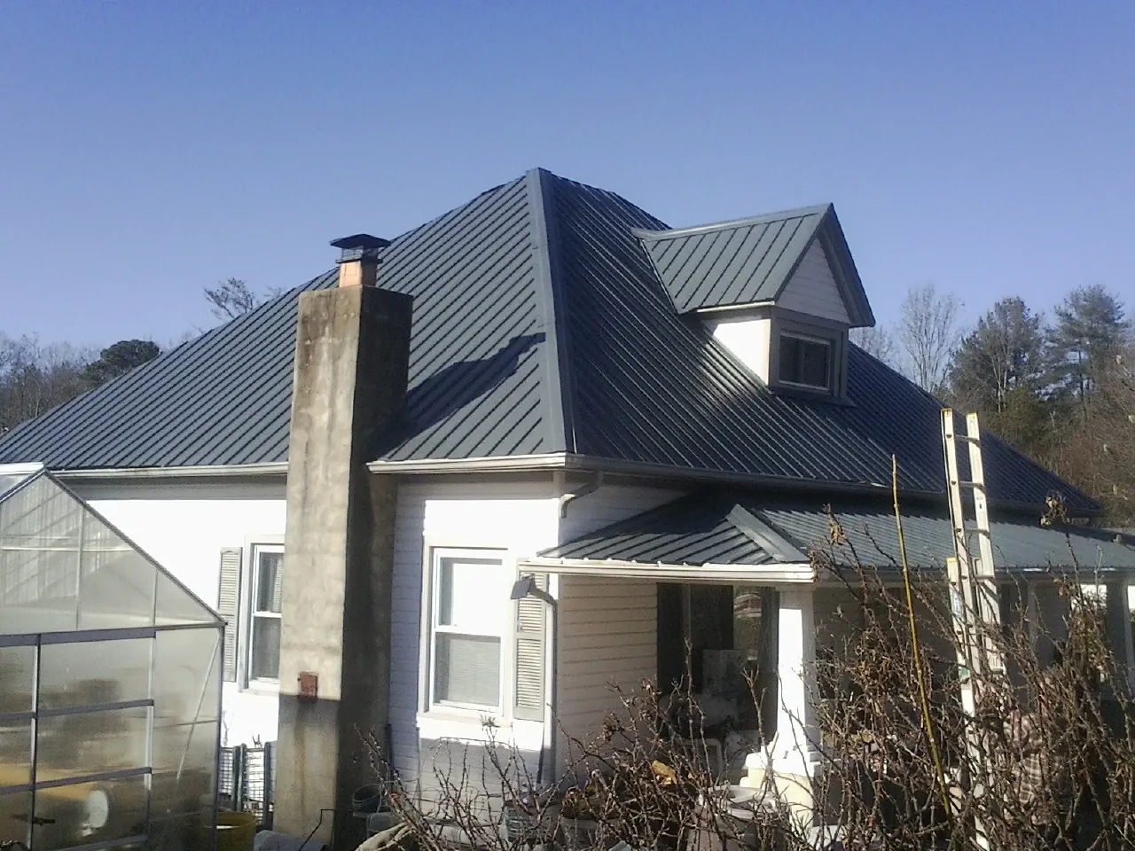 Dark blue standing seam metal roof on a white farmhouse with dormer — Slate & Tile Roof Repair by Roofing Brothers in Ledyard