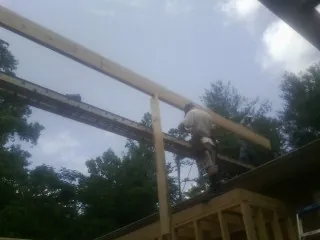 Carpenter setting a ridge beam over a new addition frame — Ice Dam Removal by Roofing Brothers in Ledyard