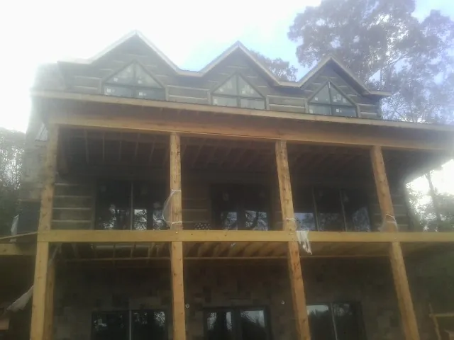 Dormers and porch framing on a large log home under construction — Roof Coating work by our crew in Ledyard