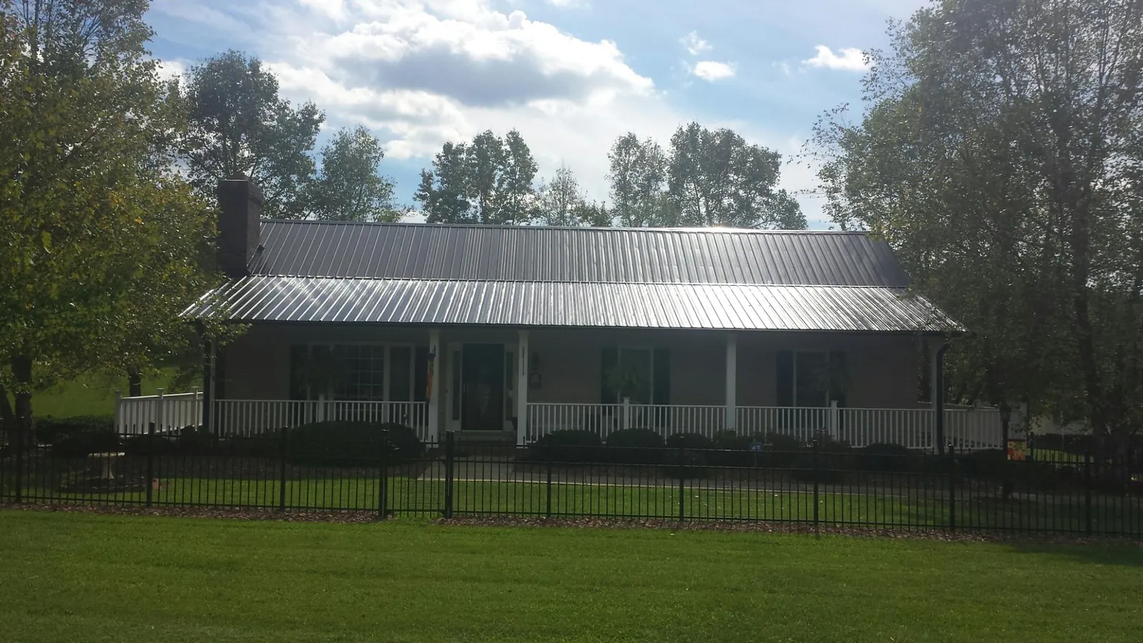 Gray metal roof on a brick ranch with a full width front porch in Ledyard